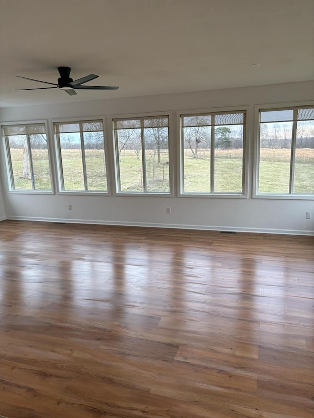 unfurnished sunroom featuring ceiling fan and a wealth of natural light