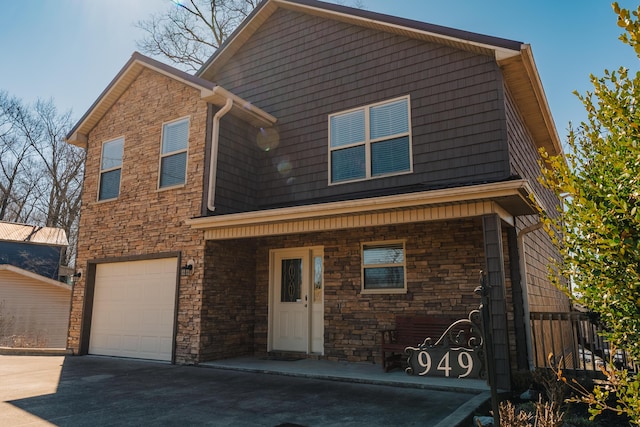 view of front of home featuring driveway, stone siding, a porch, and an attached garage