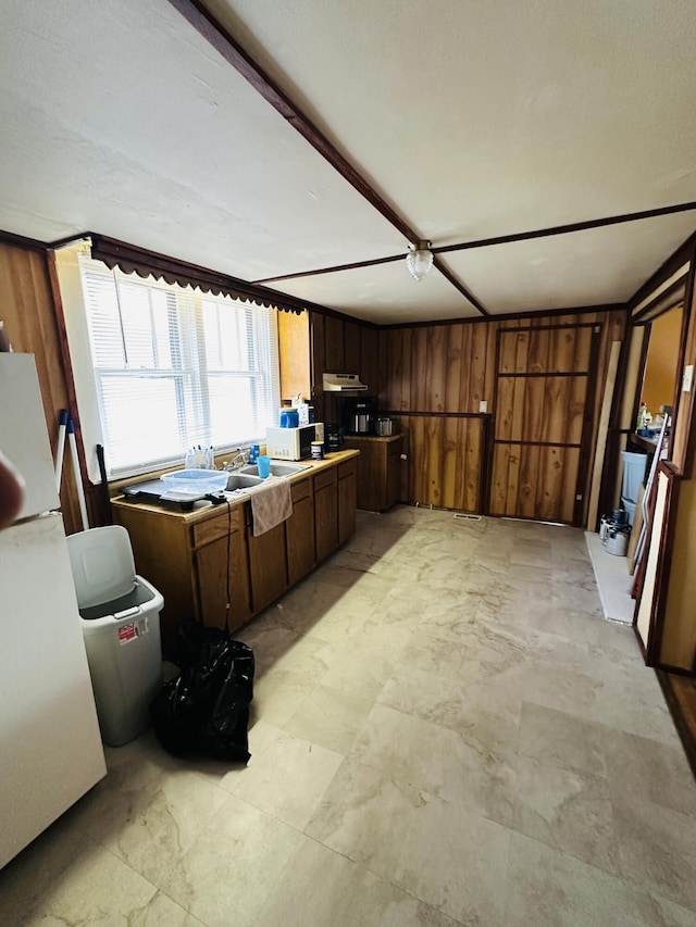 kitchen with light countertops, freestanding refrigerator, and wooden walls