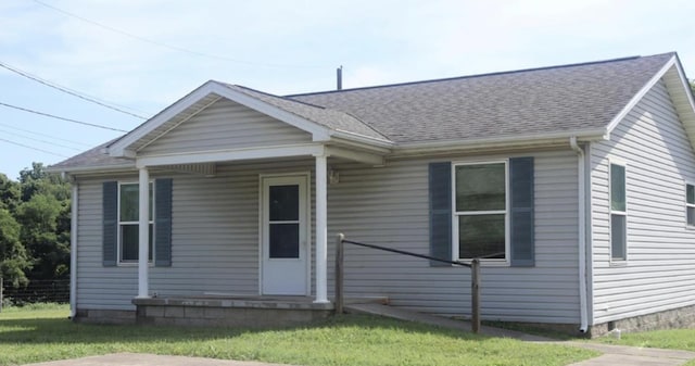 bungalow with a shingled roof and a front lawn