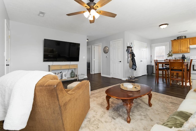 living area featuring dark wood-type flooring, baseboards, and ceiling fan