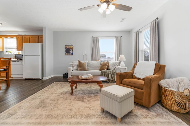 living room featuring dark wood finished floors, visible vents, baseboards, and ceiling fan