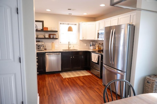 kitchen with light stone counters, a sink, visible vents, white cabinets, and appliances with stainless steel finishes