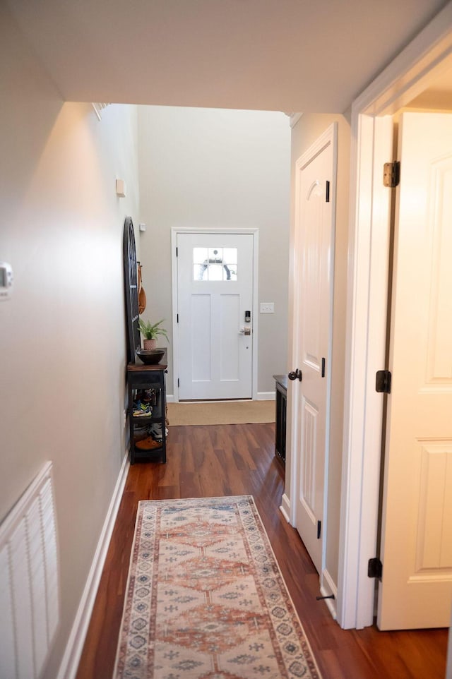 hall with dark wood-style floors, visible vents, and baseboards