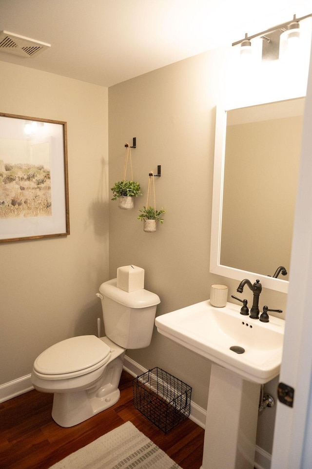 bathroom with toilet, wood finished floors, visible vents, and baseboards