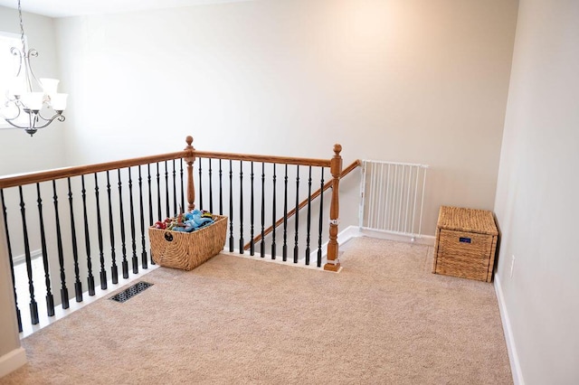 staircase featuring an inviting chandelier, carpet, visible vents, and baseboards