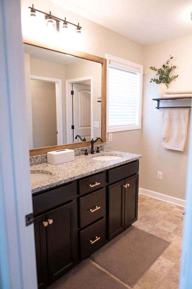 full bath featuring double vanity, baseboards, and a sink