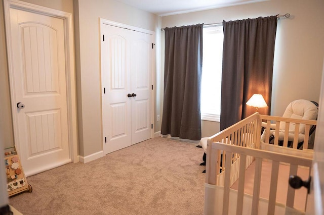 carpeted bedroom with a nursery area, a closet, and baseboards