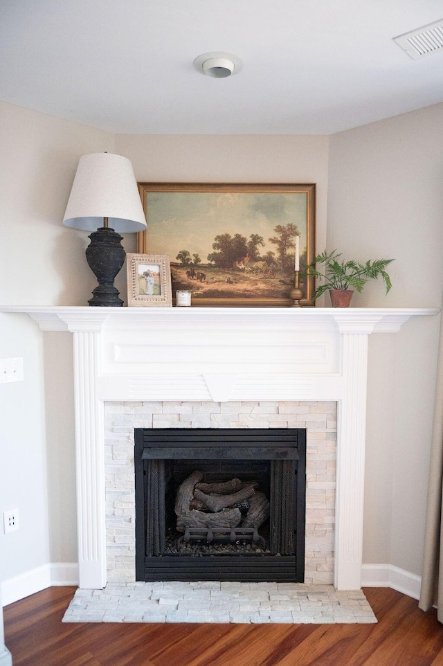 interior details with visible vents, a fireplace, baseboards, and wood finished floors