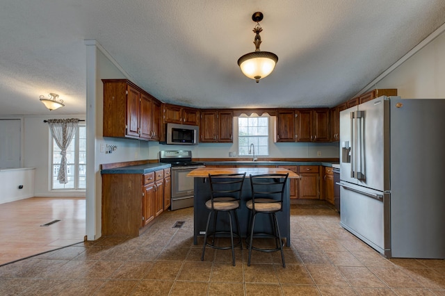 kitchen with appliances with stainless steel finishes, visible vents, a sink, and a kitchen island