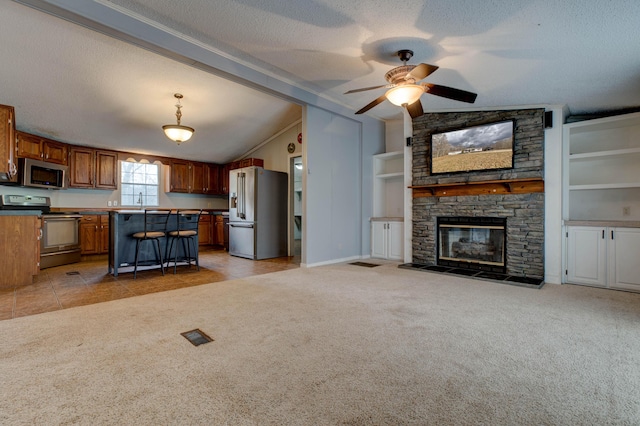 unfurnished living room featuring light carpet, visible vents, lofted ceiling, a textured ceiling, and a stone fireplace