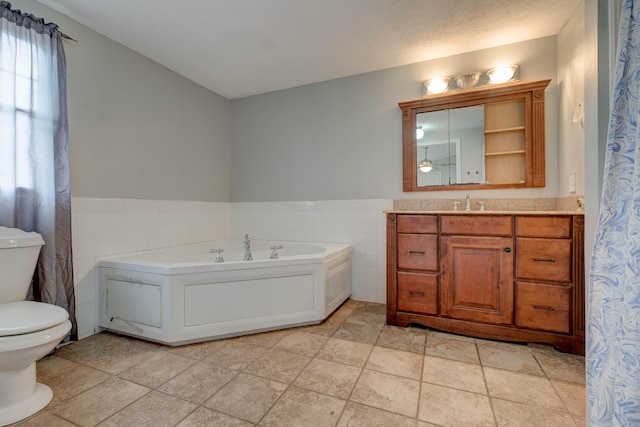 bathroom with toilet, vanity, tile walls, and wainscoting