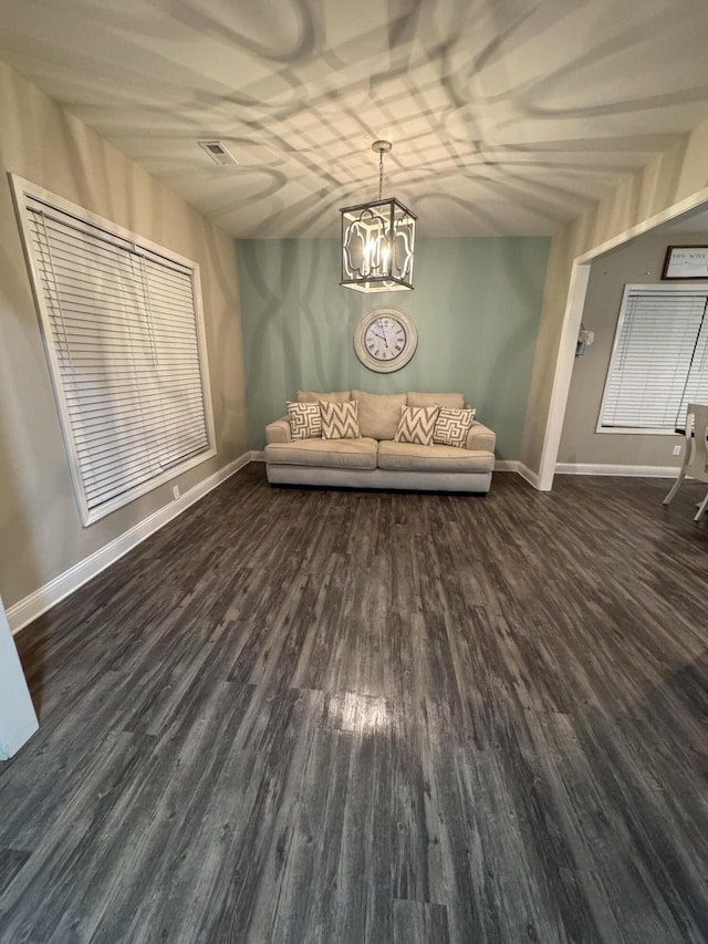 unfurnished room featuring an inviting chandelier, visible vents, wood finished floors, and baseboards