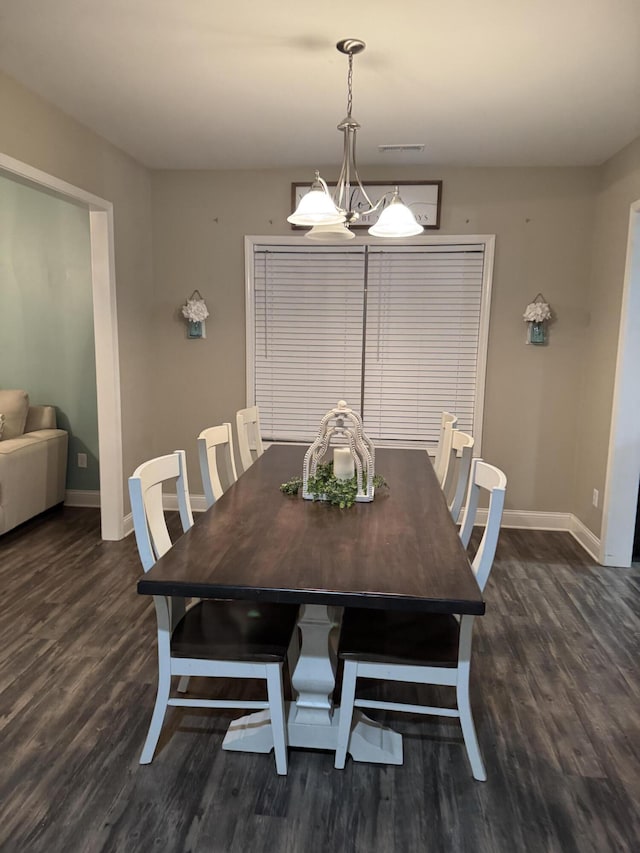 dining space with dark wood-type flooring, visible vents, baseboards, and a chandelier