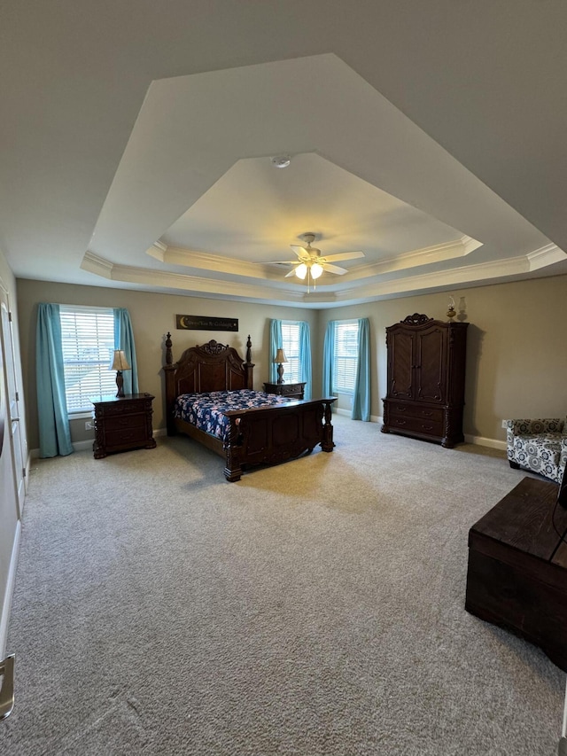 carpeted bedroom featuring ceiling fan, a raised ceiling, baseboards, and ornamental molding