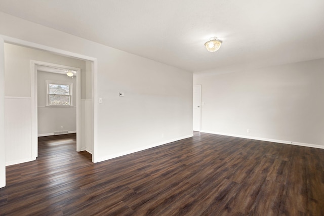 unfurnished room with visible vents, baseboards, and dark wood finished floors