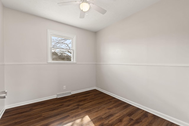 empty room with dark wood-style floors, baseboards, visible vents, and ceiling fan