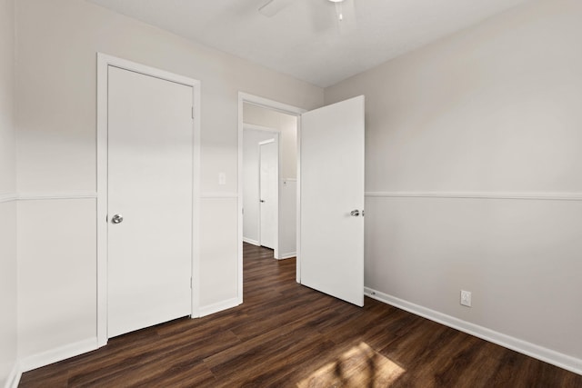 unfurnished bedroom with ceiling fan, dark wood finished floors, and baseboards