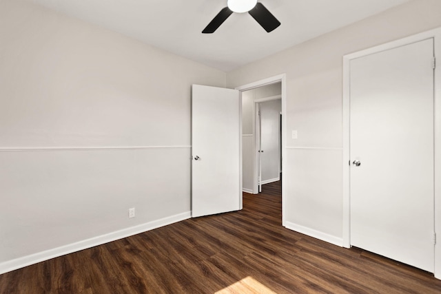 unfurnished bedroom featuring a ceiling fan, dark wood-style flooring, and baseboards