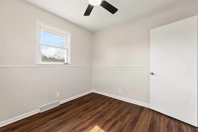 spare room with ceiling fan, dark wood-type flooring, visible vents, and baseboards