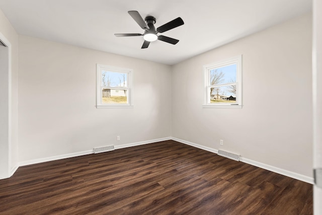 empty room with baseboards, visible vents, and dark wood-type flooring