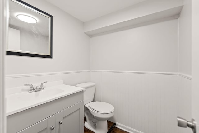 bathroom featuring toilet, wainscoting, and vanity