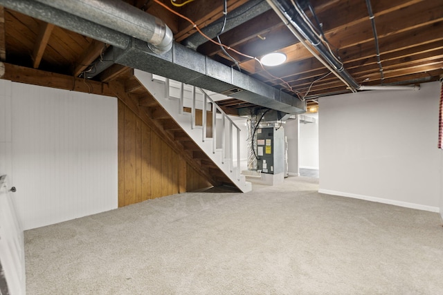 unfinished below grade area featuring heating unit, stairs, and carpet flooring