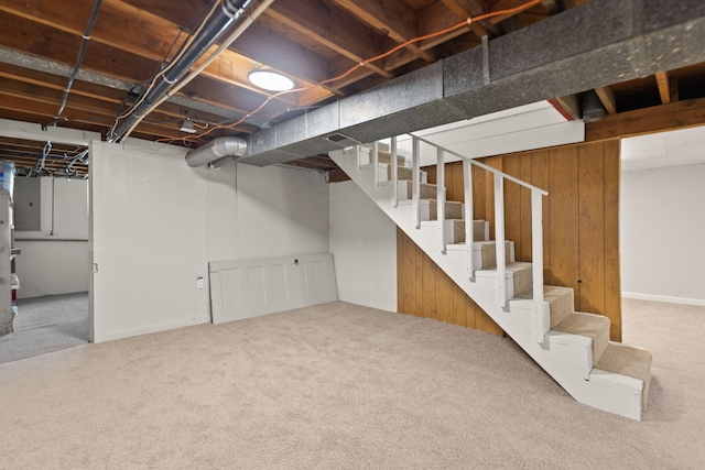 unfinished basement featuring wood walls, carpet, and stairs