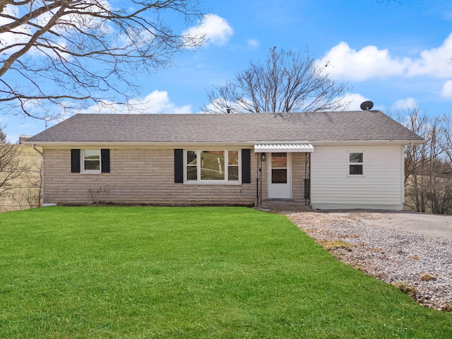 single story home with entry steps, brick siding, roof with shingles, and a front yard