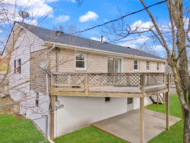 rear view of property featuring roof with shingles, a patio, a lawn, a wooden deck, and stairs