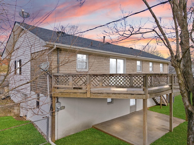 back of house at dusk featuring a patio, roof with shingles, stairs, a deck, and a yard