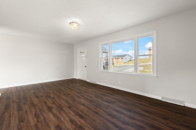 unfurnished room featuring baseboards, visible vents, and dark wood-style flooring