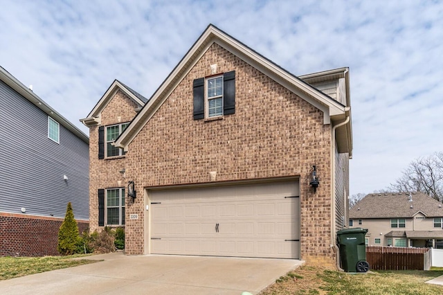 traditional home with a garage, driveway, brick siding, and fence