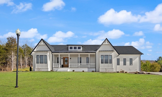 view of front facade with covered porch, roof with shingles, board and batten siding, and a front yard