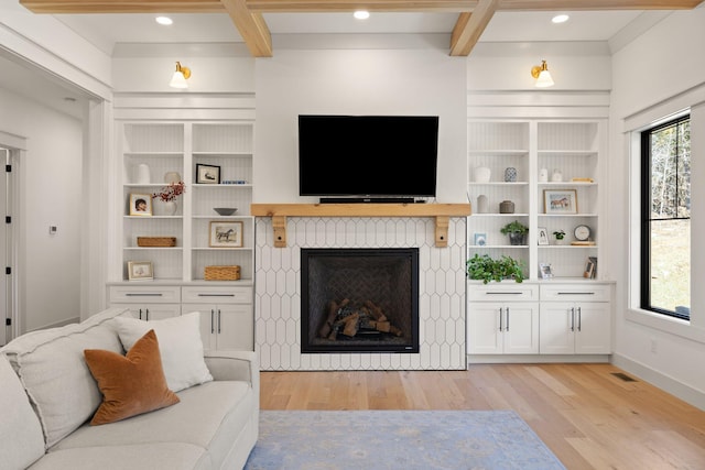 living area featuring light wood-type flooring, plenty of natural light, visible vents, and beamed ceiling