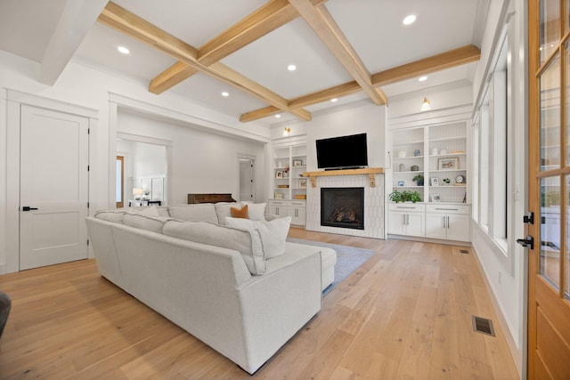 living area featuring light wood finished floors, visible vents, coffered ceiling, a fireplace, and beam ceiling