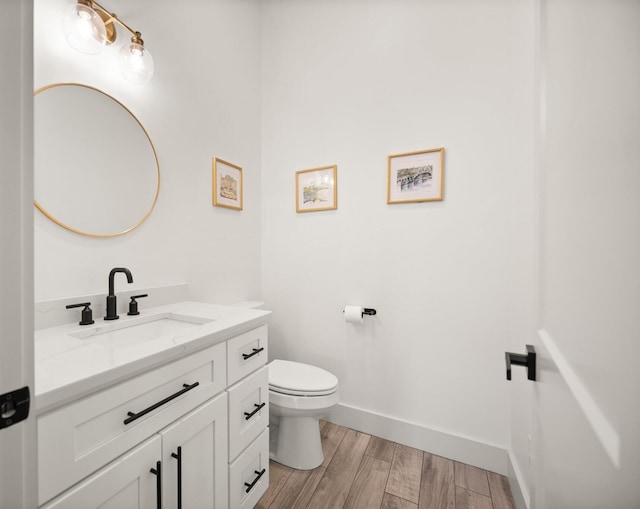 bathroom with baseboards, vanity, toilet, and wood finished floors