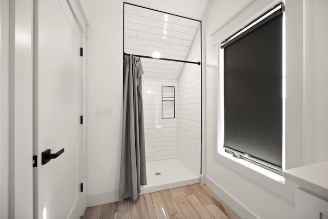 bathroom featuring a stall shower, wood finished floors, and baseboards