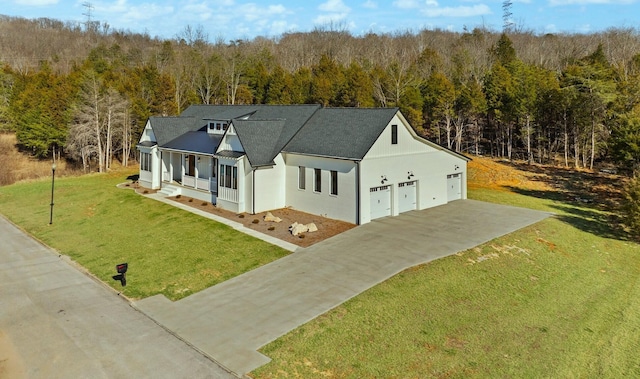 view of front facade featuring stucco siding, concrete driveway, a view of trees, a garage, and a front lawn