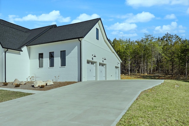 exterior space with driveway, a shingled roof, a garage, and brick siding