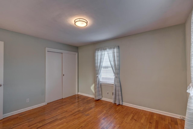 unfurnished bedroom with a closet, baseboards, and wood finished floors