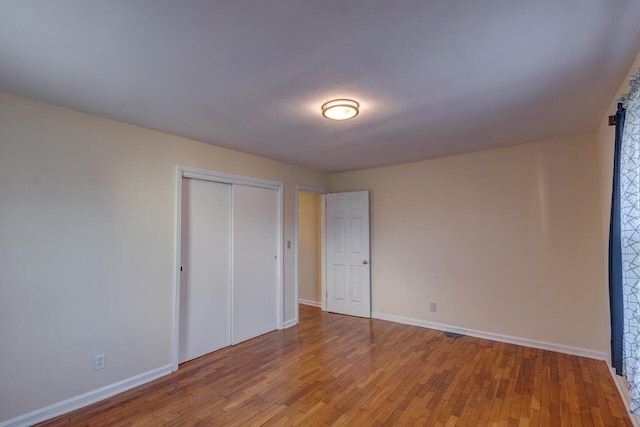 unfurnished bedroom featuring a closet, wood finished floors, and baseboards