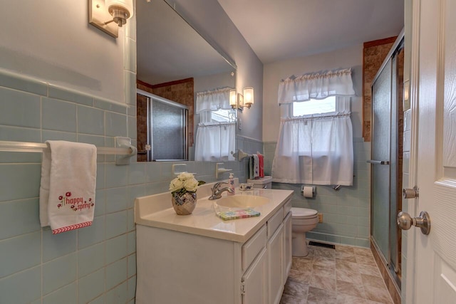 full bathroom featuring tile walls, visible vents, toilet, a stall shower, and vanity