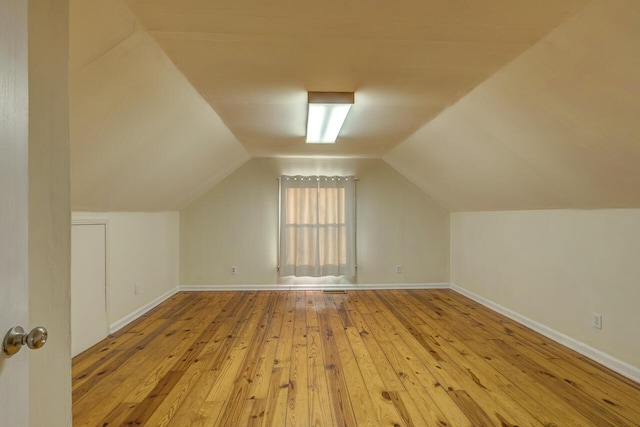 additional living space featuring vaulted ceiling, baseboards, and hardwood / wood-style flooring