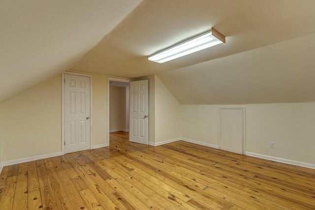 bonus room featuring light wood-type flooring, lofted ceiling, and baseboards