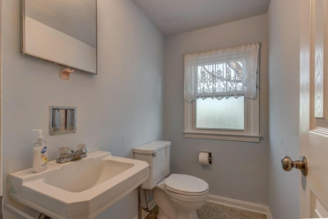 bathroom with toilet, baseboards, a sink, and speckled floor