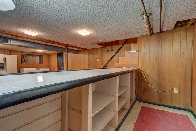 bar featuring light floors, white refrigerator with ice dispenser, and wood walls