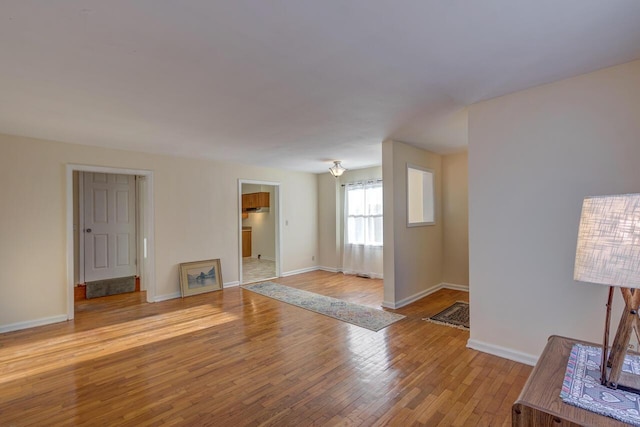 unfurnished living room with light wood finished floors and baseboards