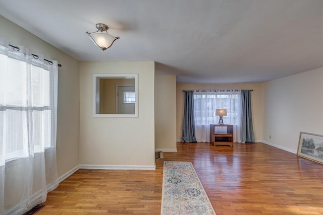 empty room with light wood-type flooring, visible vents, and baseboards