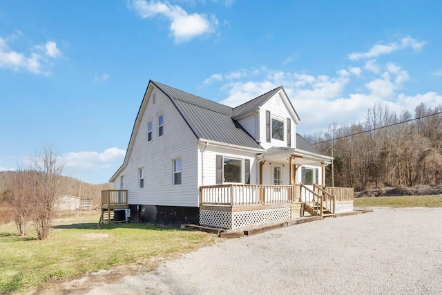 view of front of home with central air condition unit, metal roof, a front lawn, and a porch